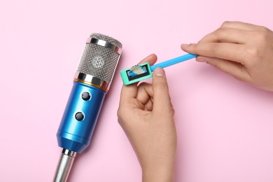 Photo of Woman making ASMR sounds with microphone, pencil and sharpener on pink background, top view