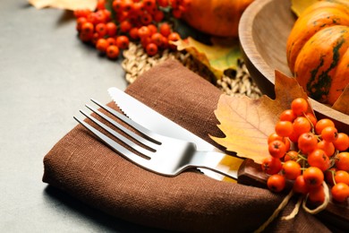 Photo of Cutlery with napkin and ashberries on grey table, closeup. Thanksgiving Day