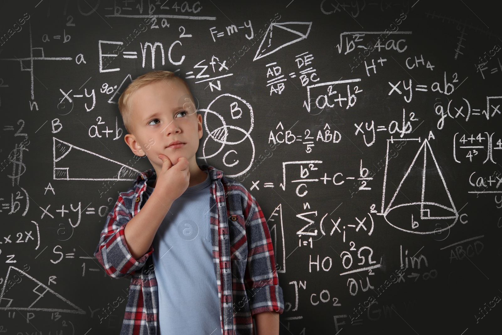 Image of Thoughtful little boy near chalkboard with different formulas