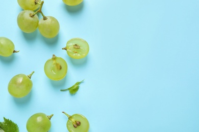 Flat lay composition with fresh ripe juicy grapes on light blue background, space for text