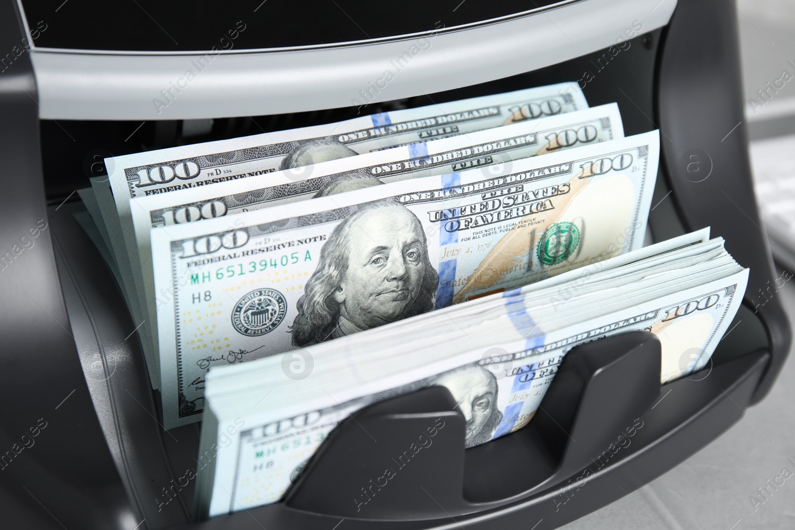 Photo of Modern electronic bill counter with money on table, closeup