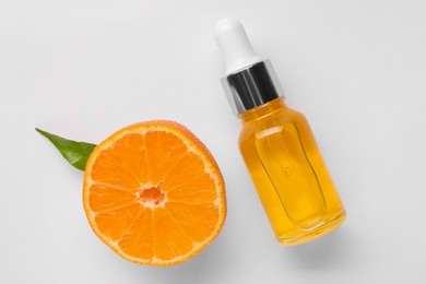 Photo of Aromatic tangerine essential oil in bottle and citrus fruit on white table, top view