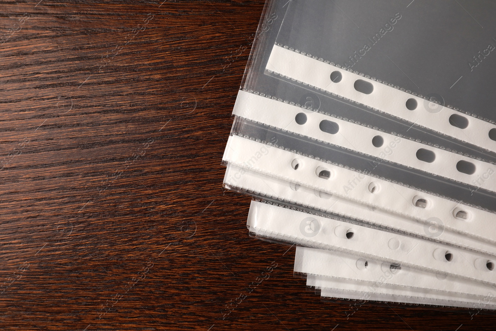 Photo of Punched pockets on wooden table, flat lay. Space for text