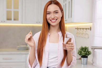 Beautiful young woman with vitamin pill and glass of water