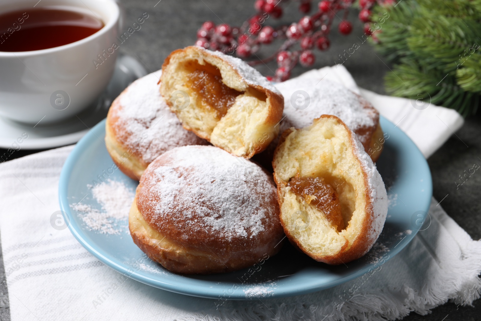 Photo of Delicious sweet buns with jam and cup of tea on table, closeup