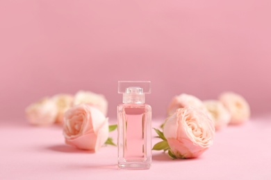 Bottle of perfume with beautiful roses on color background