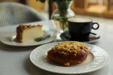 Photo of Fresh bun, tasty cheesecake and cup of coffee on table indoors