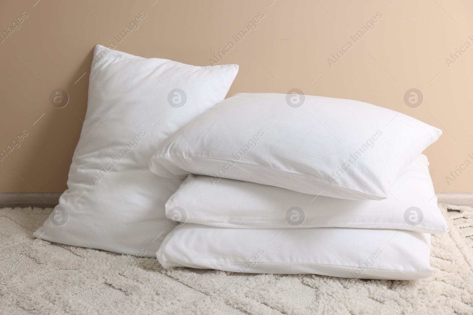 Photo of Soft white pillows near beige wall indoors