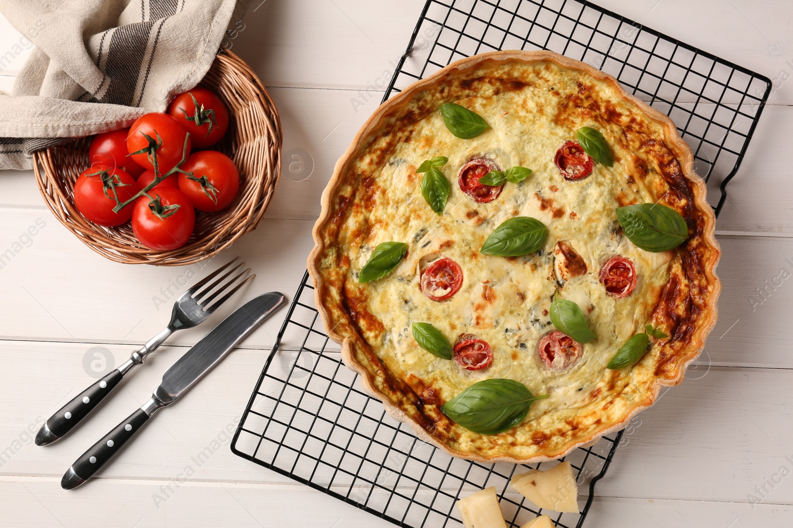 Photo of Delicious homemade cheese quiche, ingredients and cutlery on white wooden table, flat lay