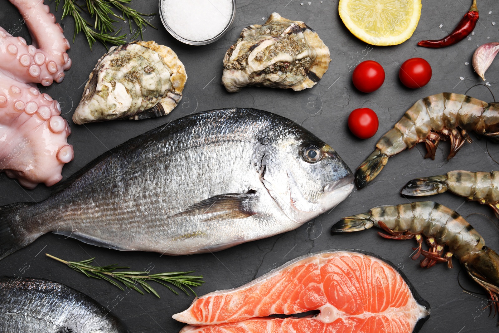 Photo of Flat lay composition with fresh raw dorado fish and different seafood on black table