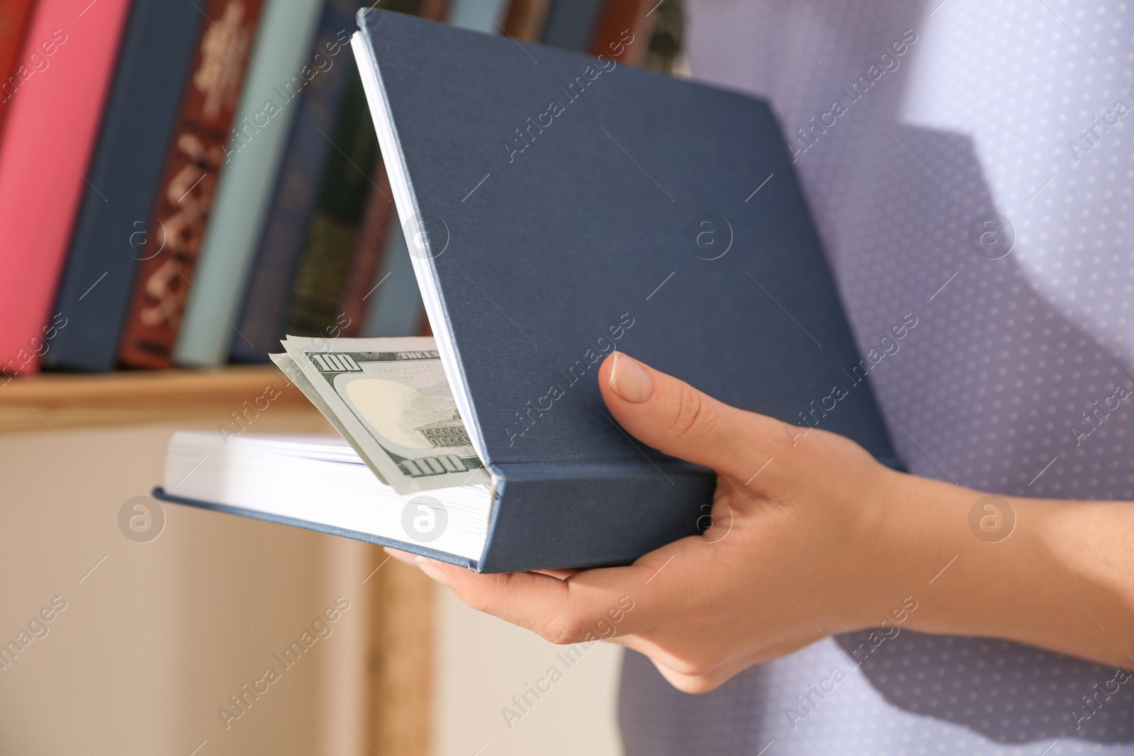 Photo of Woman hiding money in book indoors, closeup. Financial savings