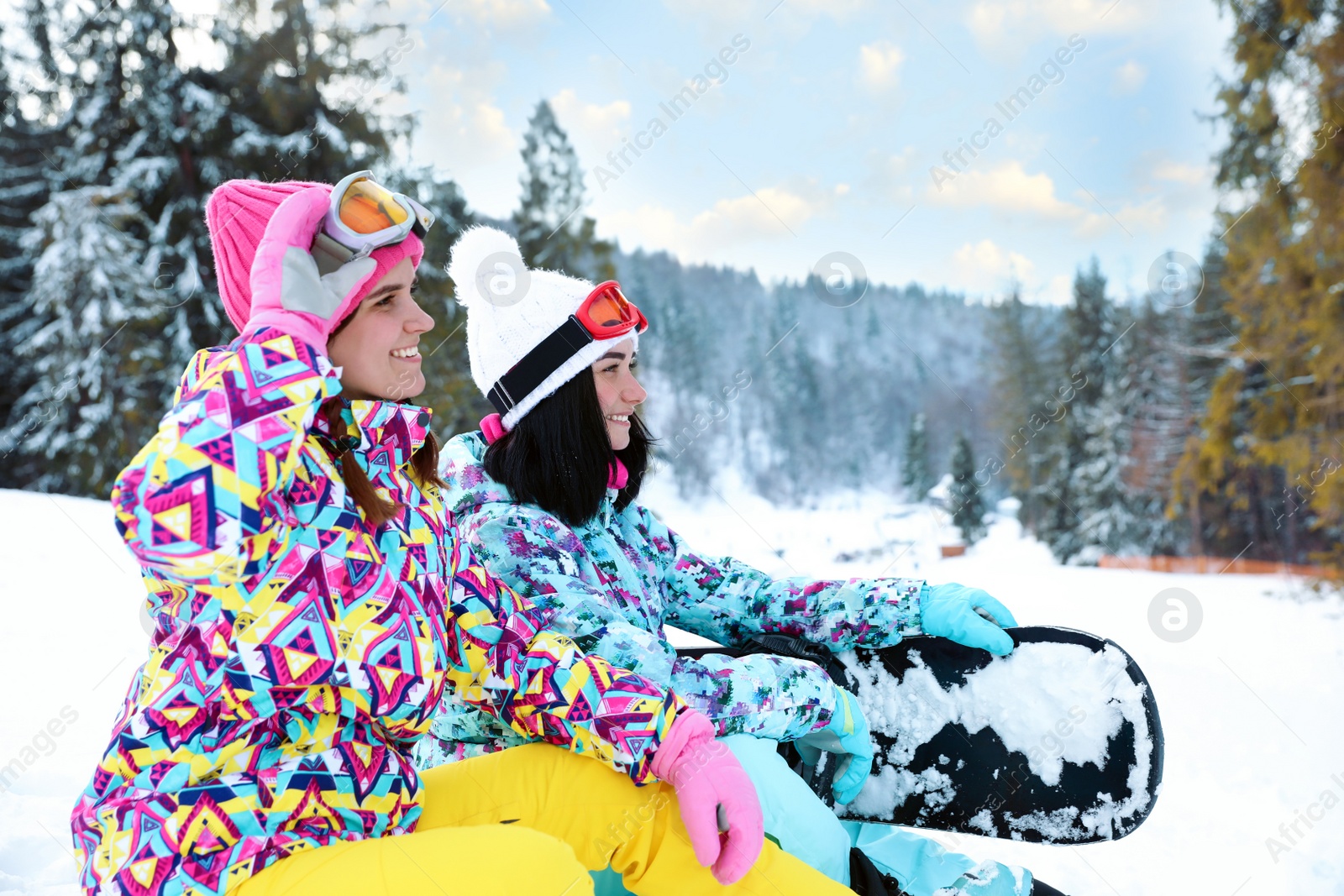 Photo of Friends resting on hill at mountain resort. Winter vacation