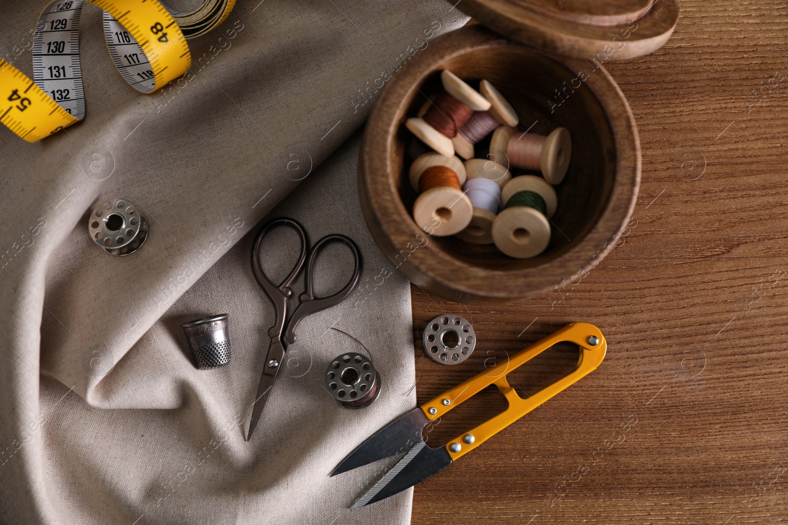 Photo of Set of sewing supplies and accessories on wooden table, flat lay