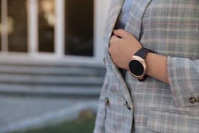 Photo of Young woman with smart watch outdoors, closeup. Space for text