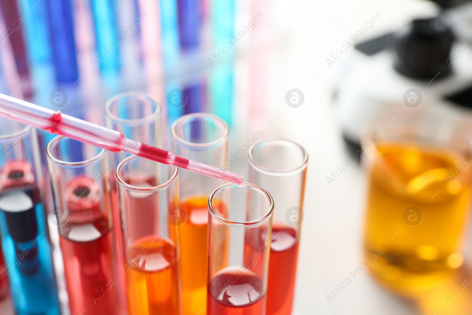 Photo of Dripping reagent into test tube with sample in chemistry laboratory, closeup. Space for text