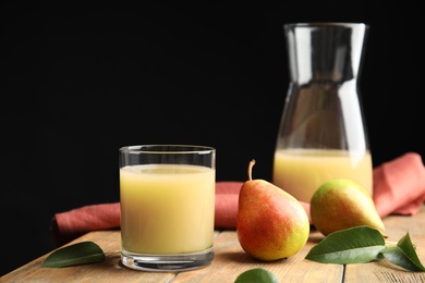 Fresh pear juice in glass and fruits on wooden table