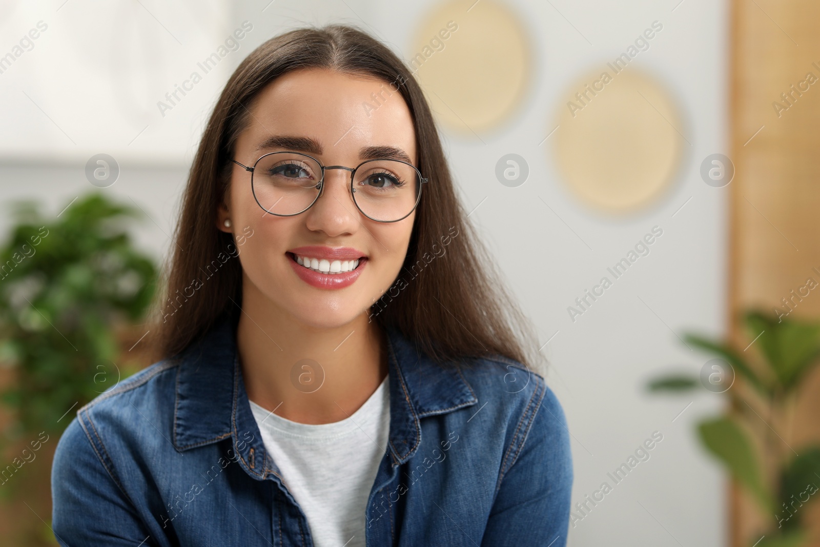 Photo of Portrait of beautiful young woman with glasses indoors. Attractive lady smiling and looking into camera