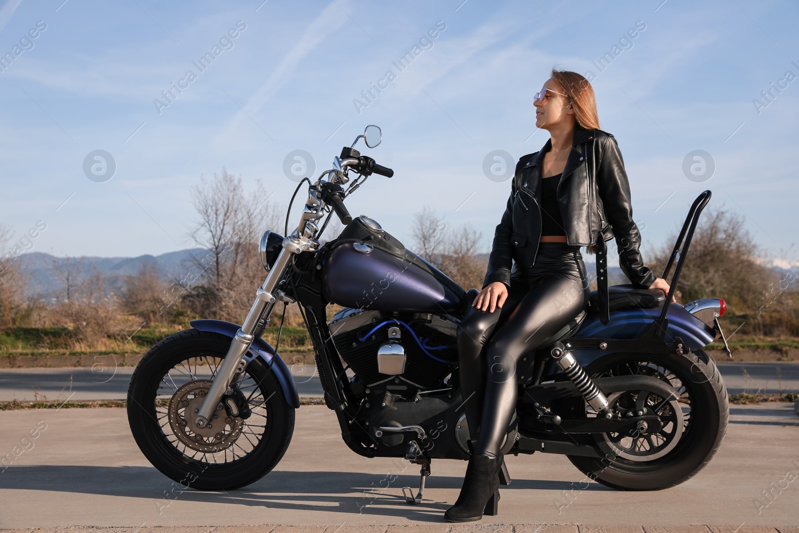 Photo of Beautiful young woman sitting on motorcycle outdoors