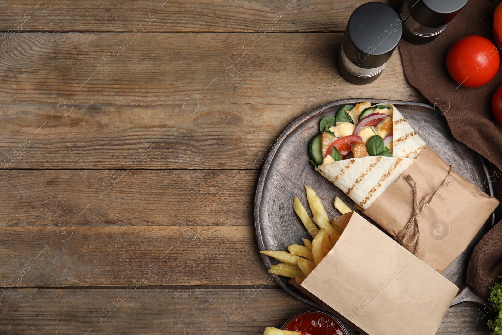 Photo of Delicious chicken shawarma and French fries served on wooden table, flat lay. Space for text