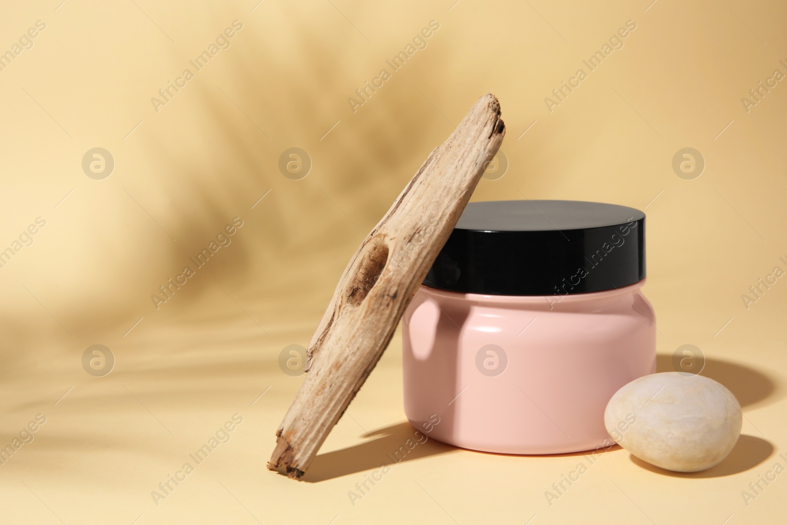 Photo of Jar of cream, stick and stone on beige background. Space for text