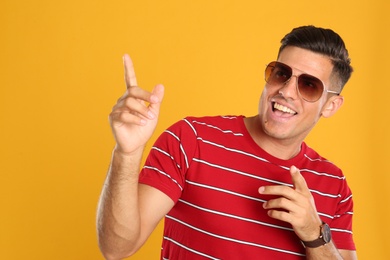 Photo of Handsome man wearing sunglasses on yellow background