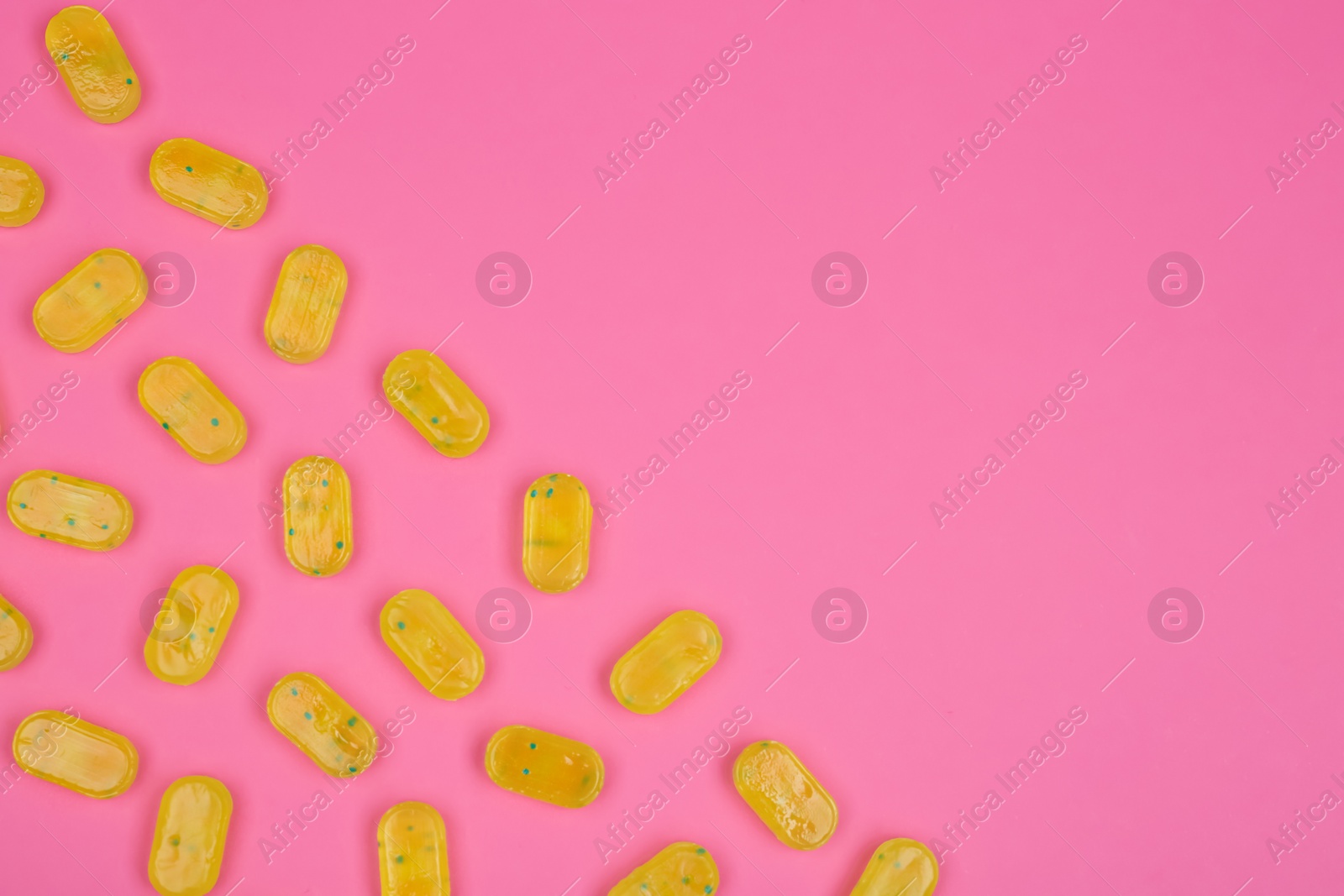 Photo of Many delicious lemon drops on pink background, flat lay. Space for text