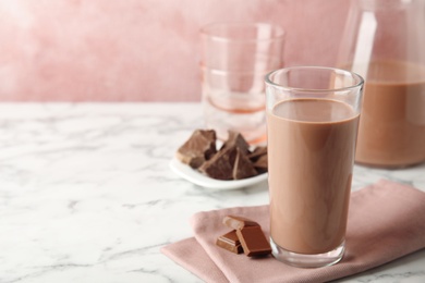 Glass with tasty chocolate milk on marble table, space for text. Dairy drink