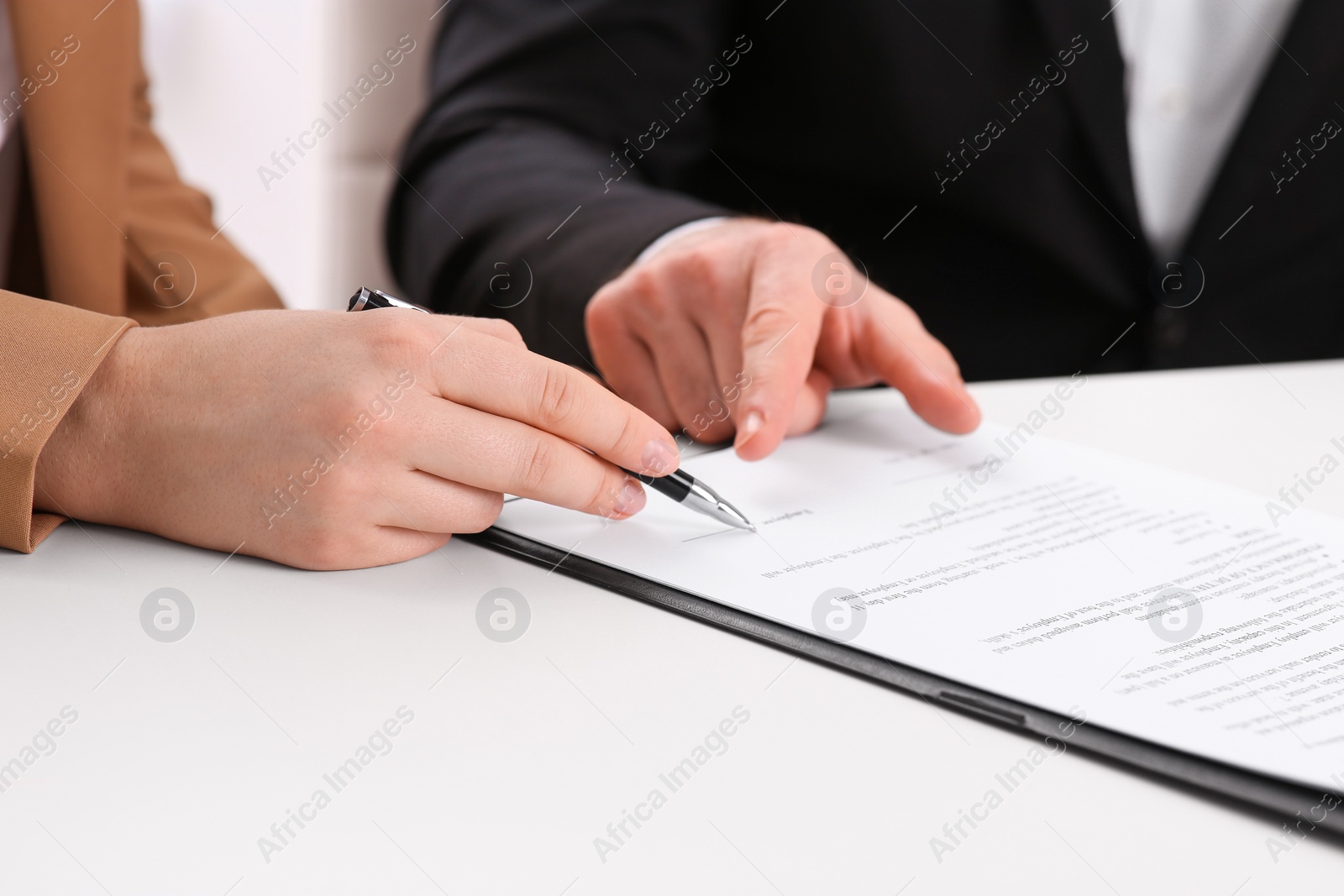 Photo of Businesspeople signing contract at white table, closeup of hands