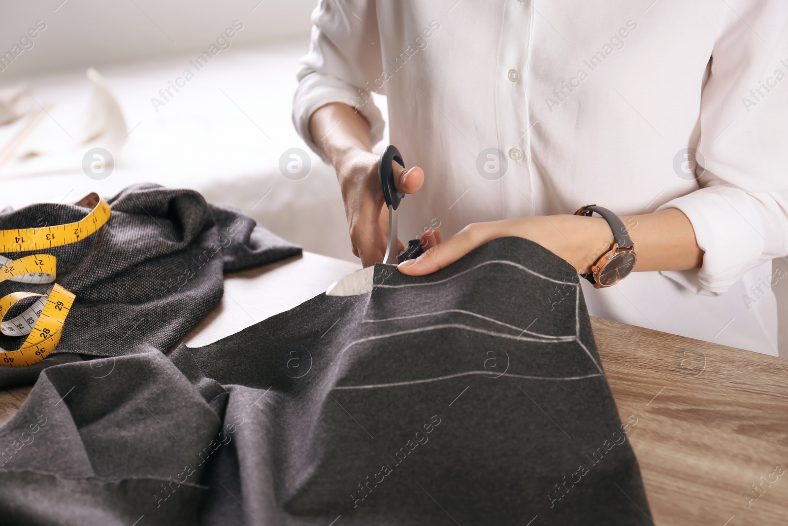 Photo of Tailor working with cloth at table in atelier