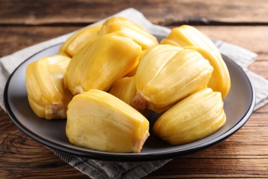 Photo of Delicious exotic jackfruit bulbs on wooden table, closeup