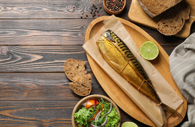 Flat lay composition with tasty smoked fish on wooden table. Space for text