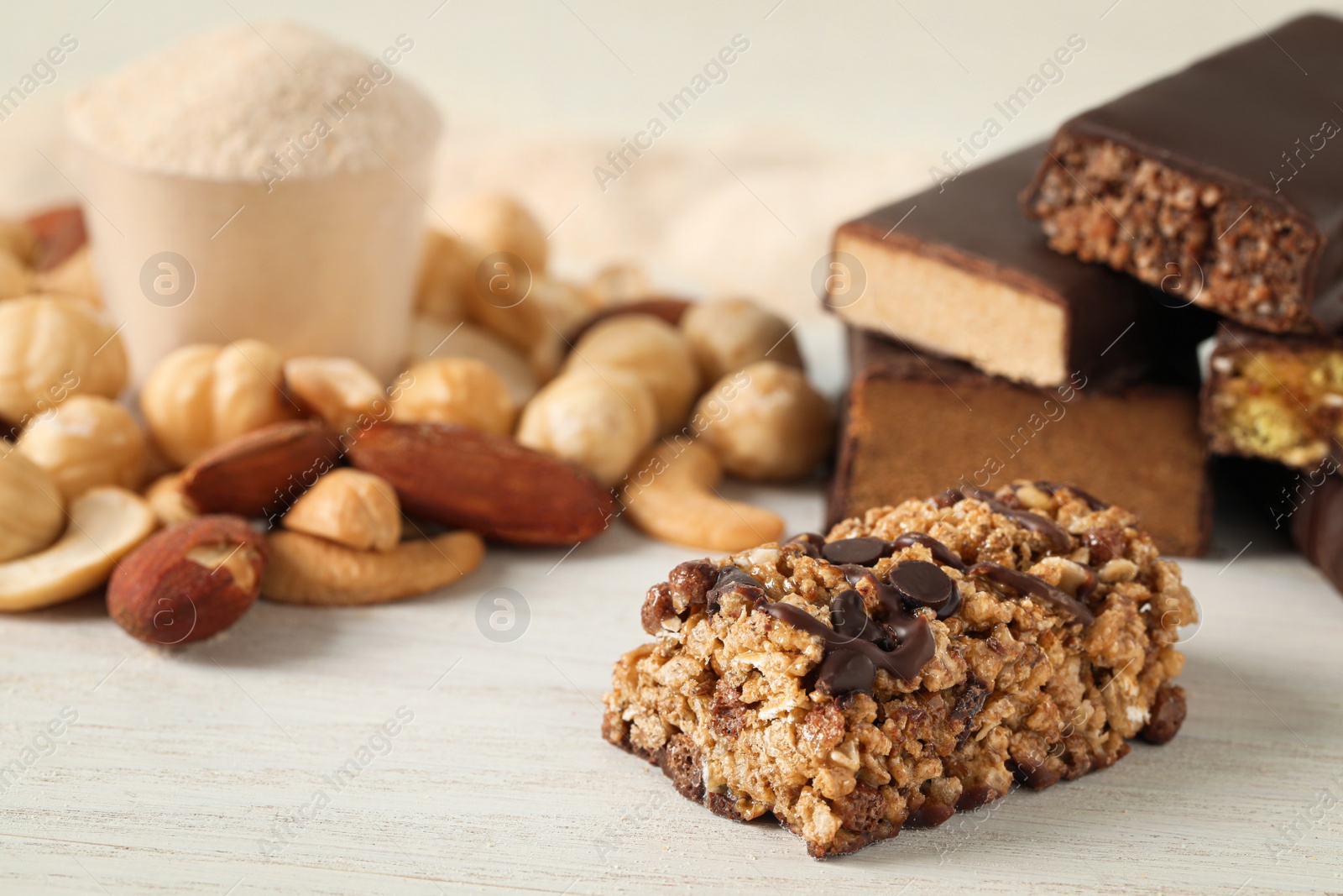 Photo of Different tasty protein bars and nuts on white table, closeup
