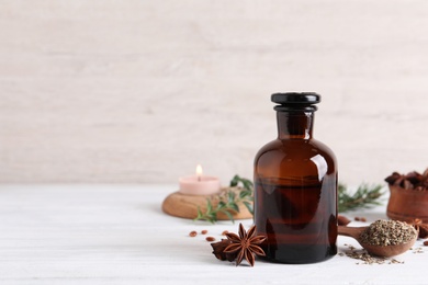 Anise essential oil and spice on white table, space for text