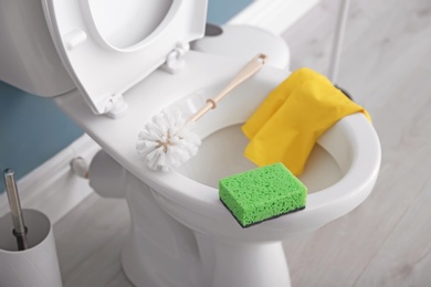 Ceramic toilet bowl and cleaning supplies in modern bathroom