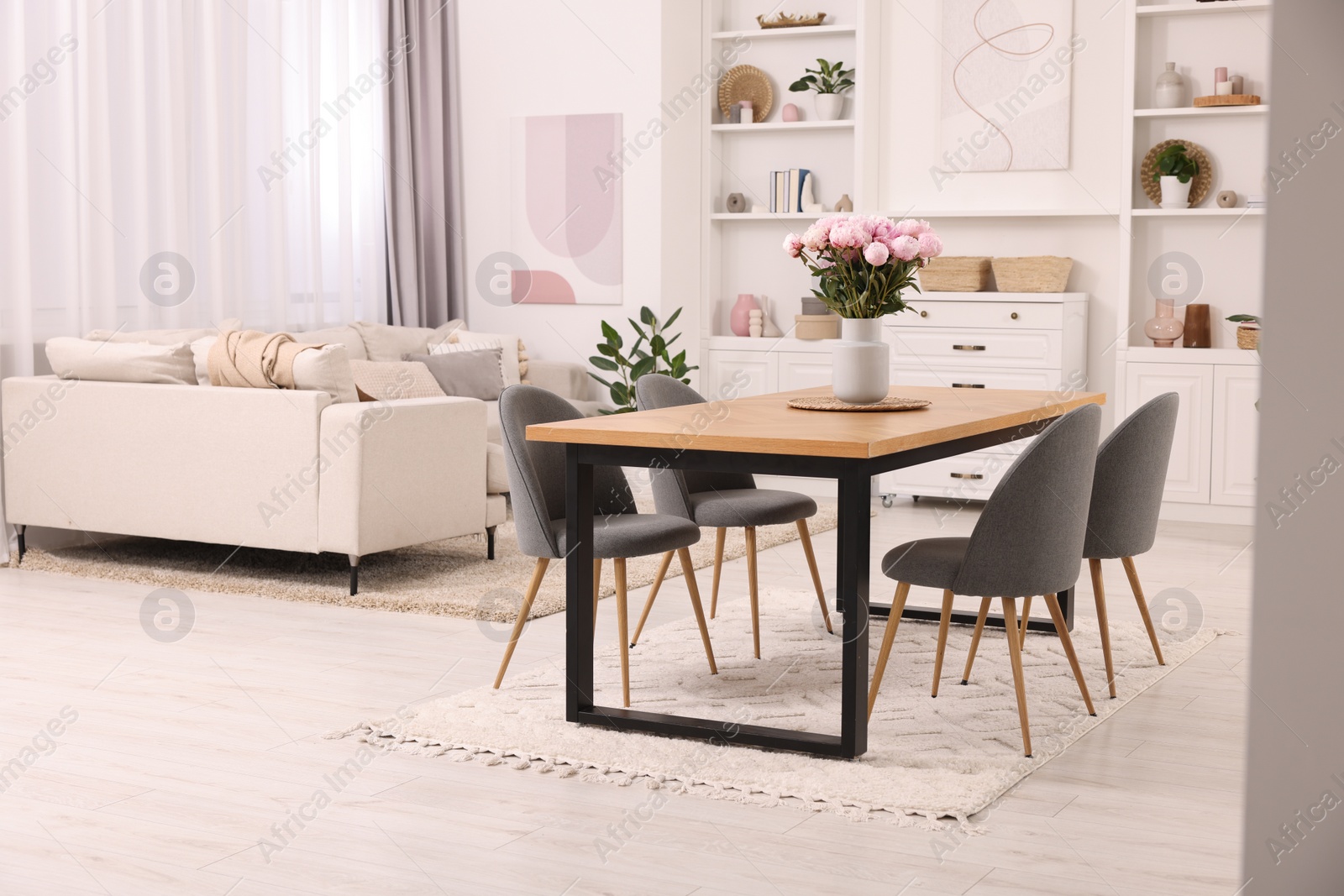 Photo of Stylish dining room with cosy furniture and flowers