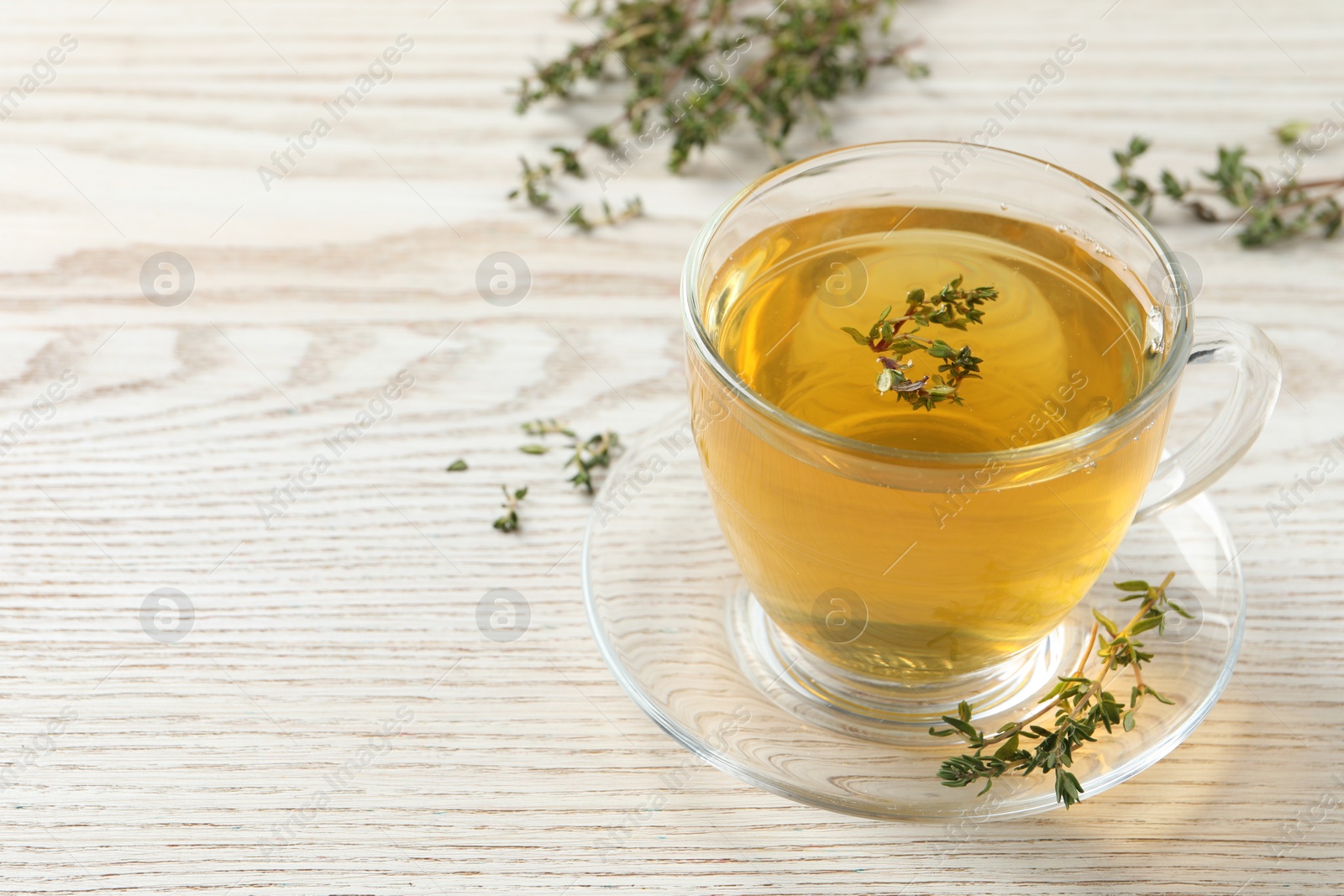 Photo of Aromatic herbal tea with thyme on white wooden table, space for text