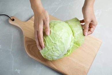 Photo of Woman with ripe cabbage at table, top view