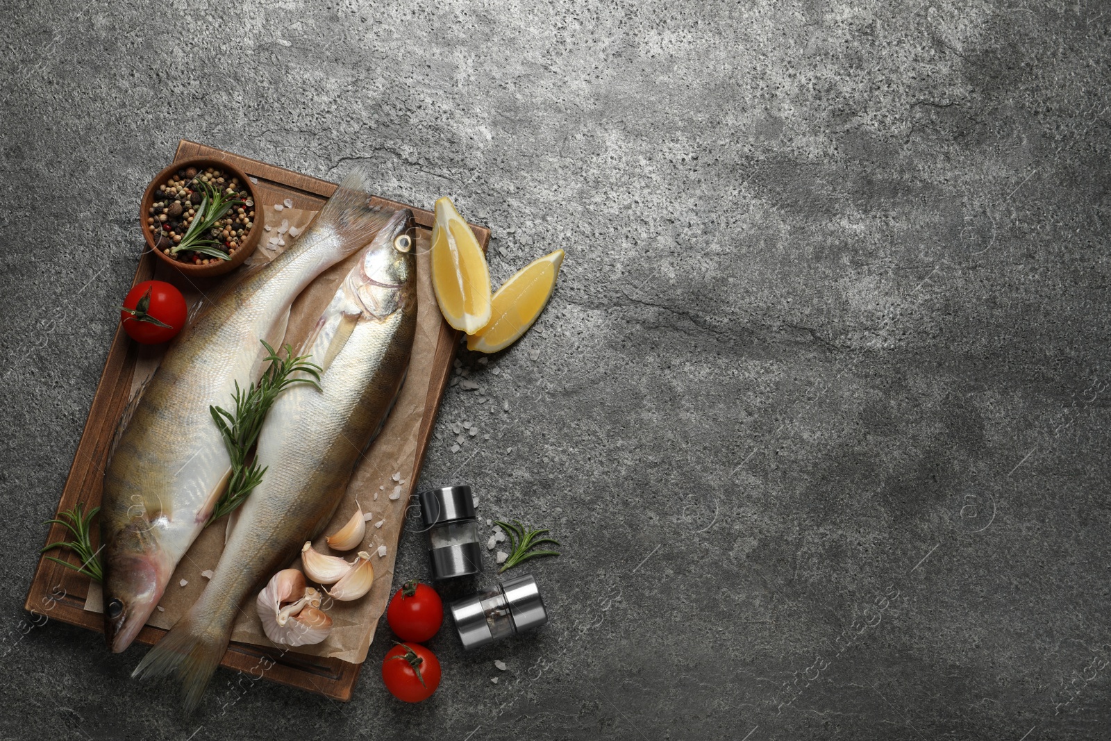 Photo of Fresh raw pike perches and ingredients on grey table, flat lay with space for text. River fish