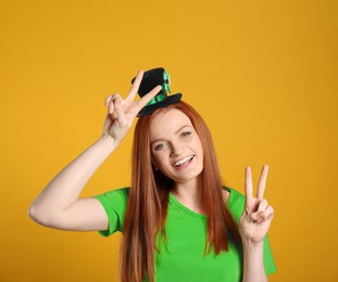 Image of St. Patrick's day party. Pretty woman in leprechaun hat on golden background