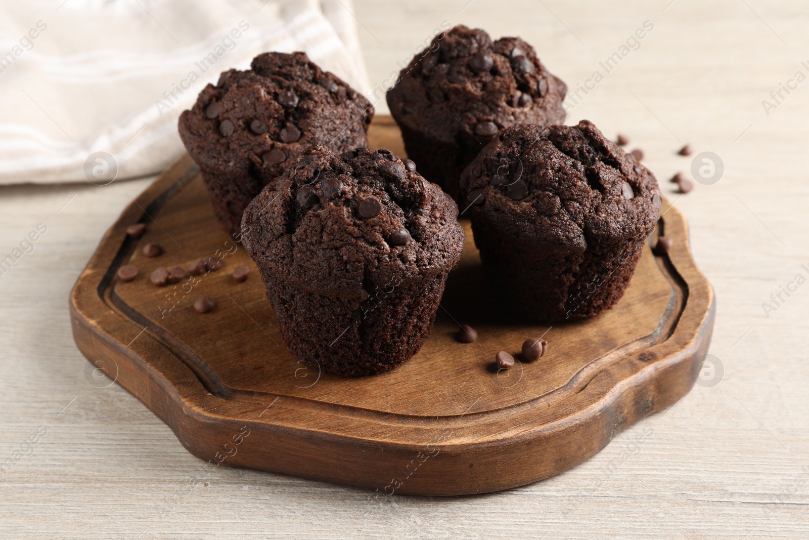 Photo of Delicious chocolate muffins on white wooden table