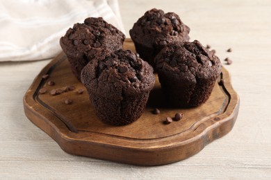 Delicious chocolate muffins on white wooden table