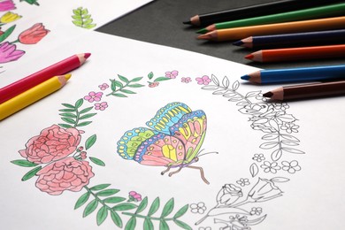 Coloring page with children drawing and set of pencils on grey table, closeup