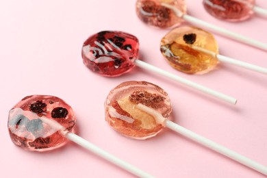 Sweet colorful lollipops with berries on pink background, closeup