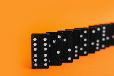 Photo of Brown domino tiles with white pips on orange background