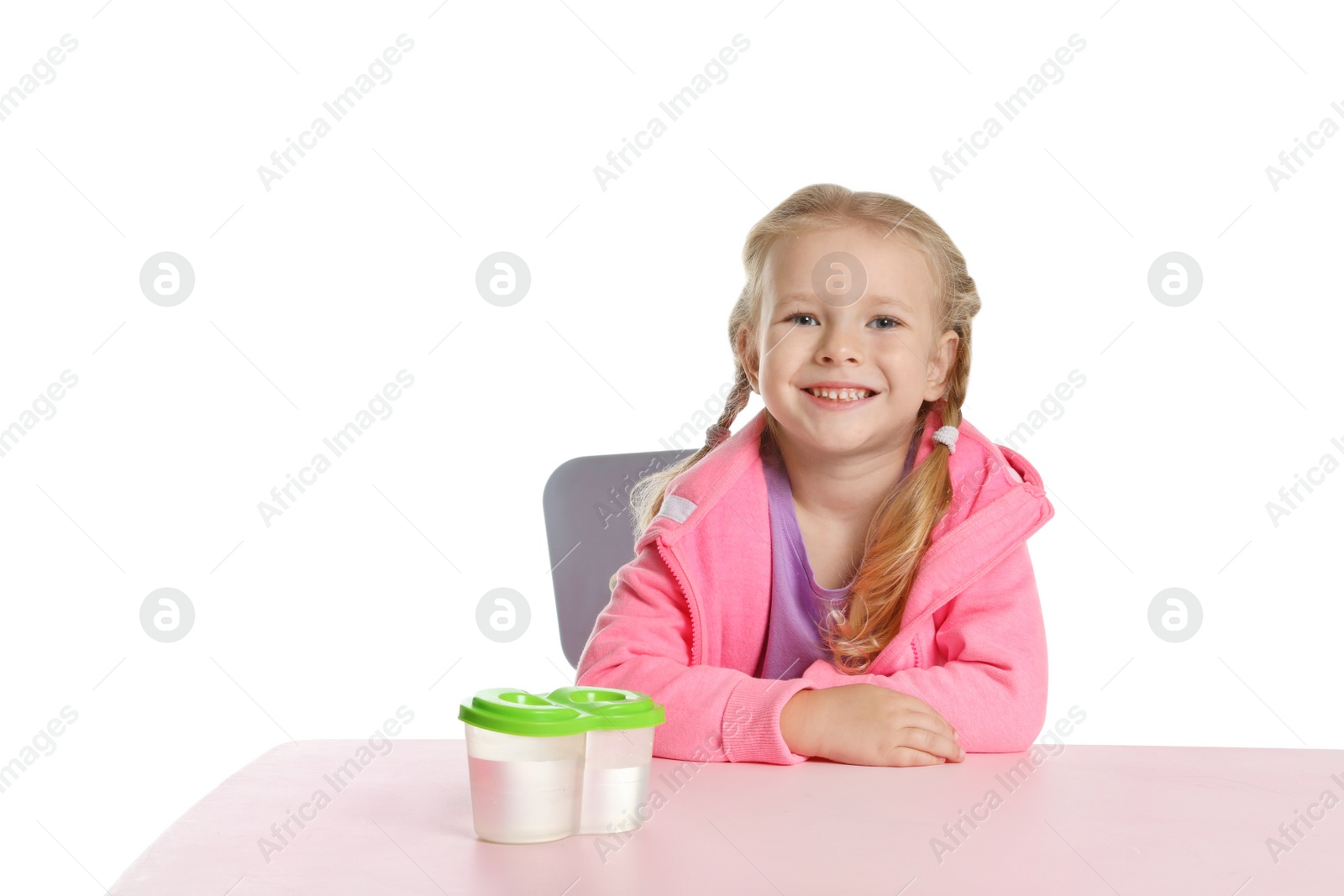 Photo of Cute little child with water cups at table on white background. Painting accessory