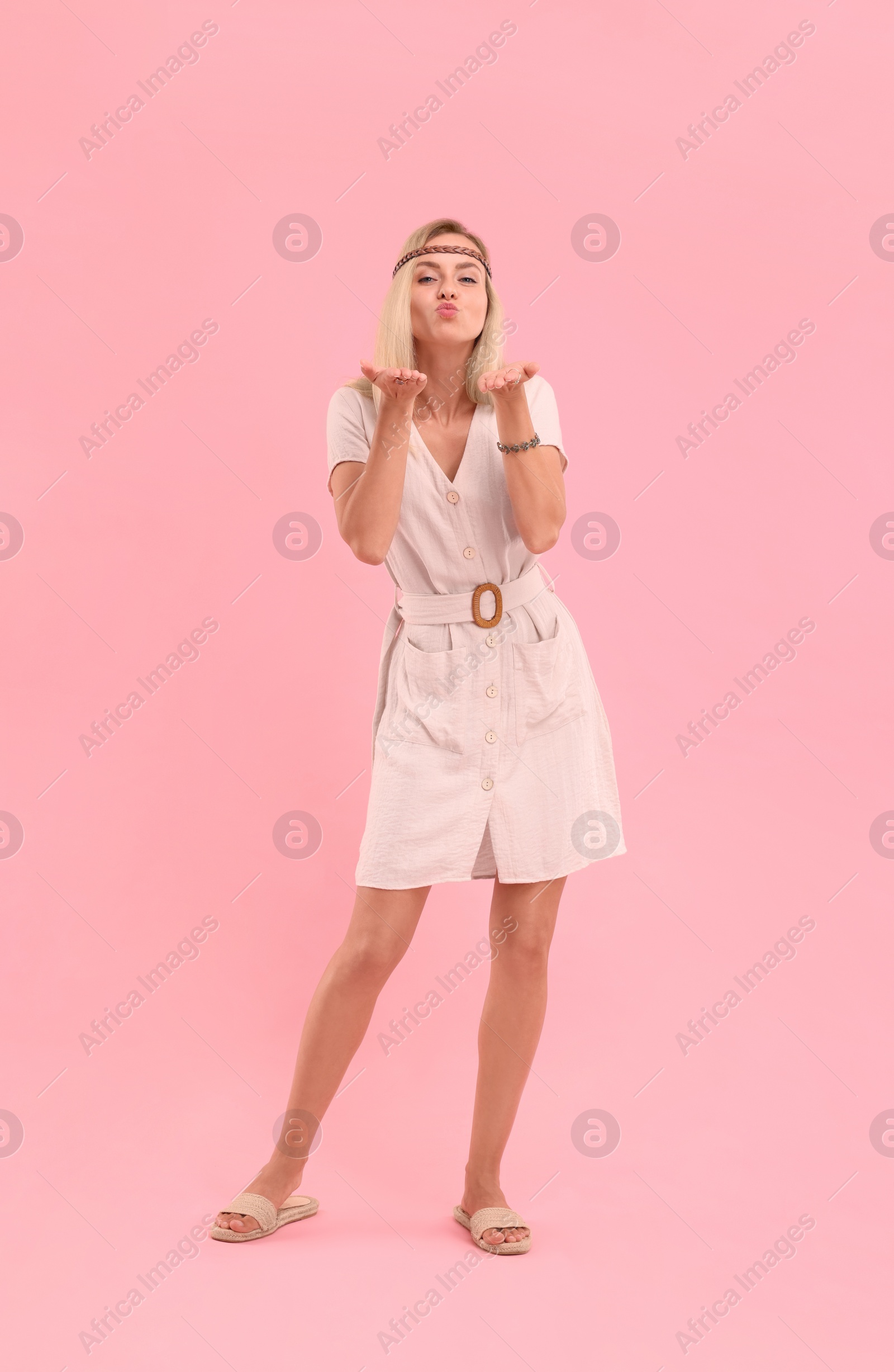 Photo of Beautiful hippie woman blowing kiss on pink background