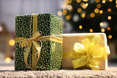 Beautiful Christmas gifts with golden bows on carpet indoors