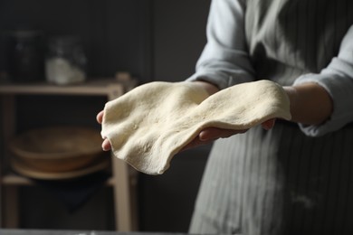 Woman tossing pizza dough in kitchen, closeup