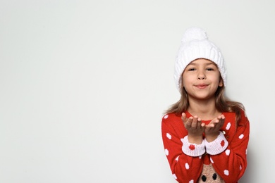 Photo of Cute little girl in Christmas sweater and knitted hat on white background. Space for text