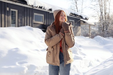 Portrait of beautiful young woman on snowy day outdoors. Winter vacation